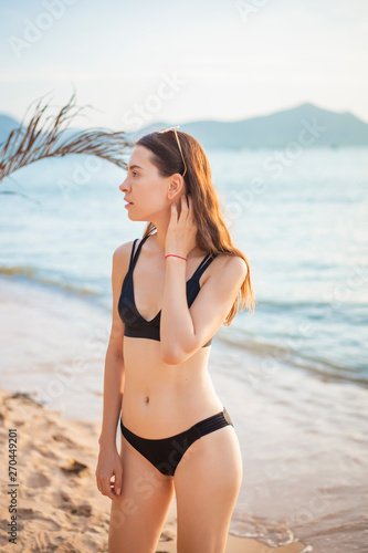 Beautiful woman in black bikini is relaxing on the beach, summer concept © tonefotografia