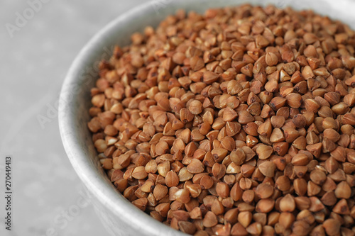 Uncooked buckwheat in bowl on table, closeup