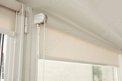 Window with modern roll blinds in room, closeup