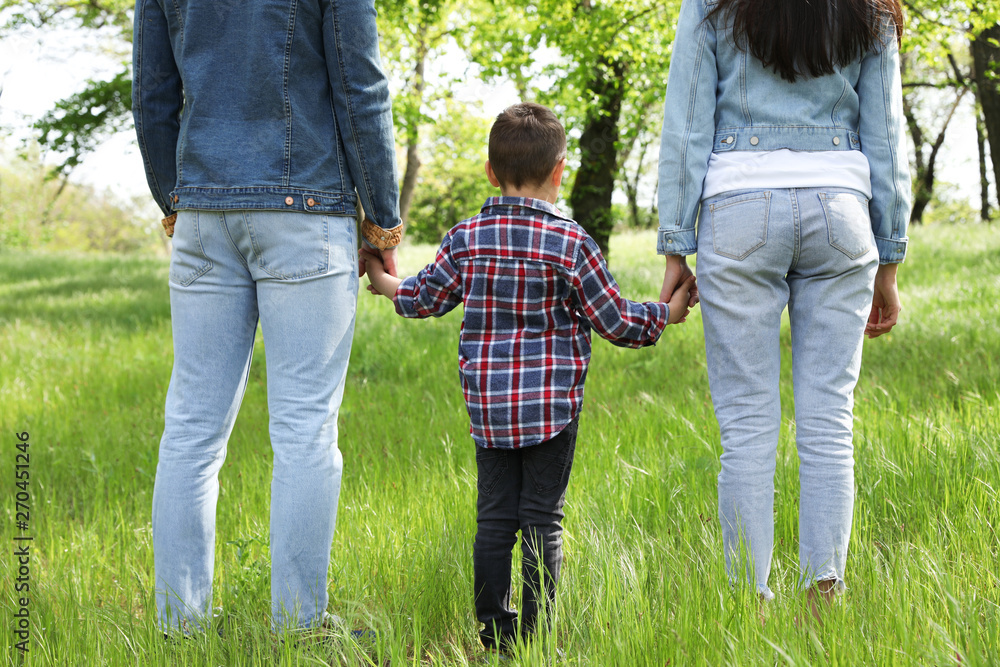 Little child holding hands with his parents in park. Family time Little child holding hands with his parents in park. Family time