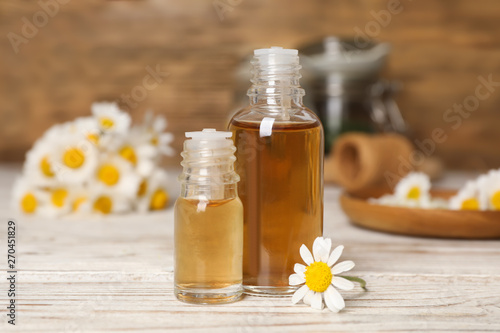 Composition with bottles of chamomile essential oil on table