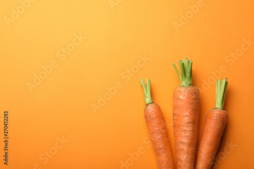 Flat lay composition with fresh carrots on color background. Space for text
