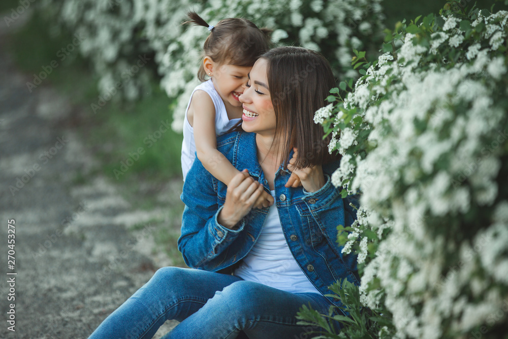 Cute mother and daughter together. Happy family outdoors. Girls in flowers. Ypung woman and her child on summer background. Cute mother and daughter together. Happy family outdoors. Girls in flowers. Ypung woman and her child on summer background.