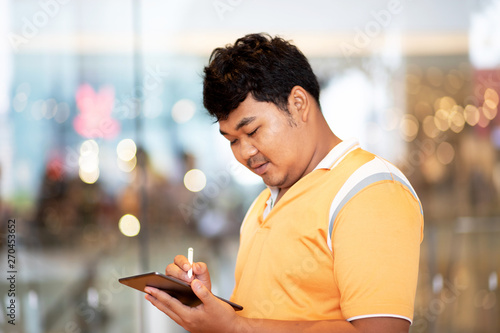 Asian man holding stylus pen and tablet writing down on tablet