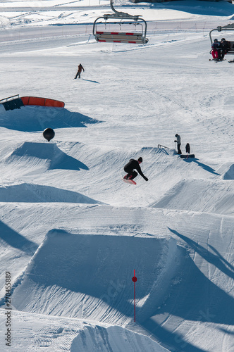 Billede på lærred A snowboarder hitting his jump off the kicker in the snowpark