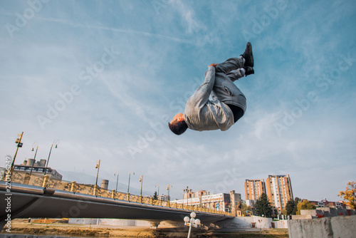 Sportive man make parkour tricks while jumping