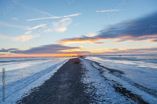 Sunset over long peninsula in shallow Baltic sea, frosty winter time. Path to the sun.