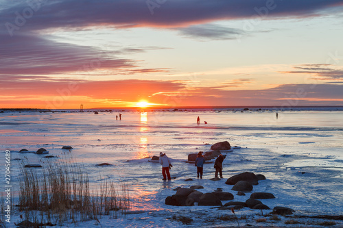 People walking on the frozen sea surface at sunset, Estonia. © yegorov_nick