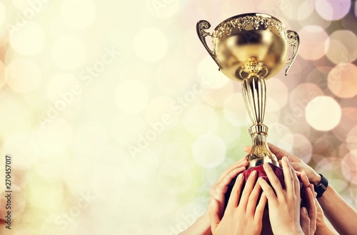 Hand holding golden Trophy on bokeh background