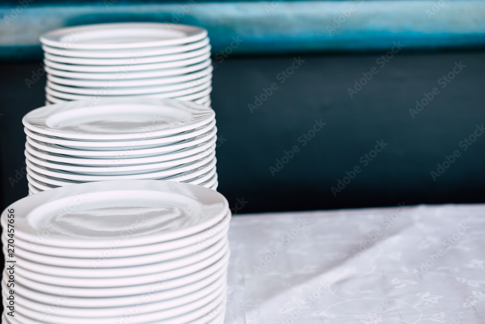 Obraz premium Pile of white clean dishes on a table - close up of kitchen stuffs for catering or restaurant business concept