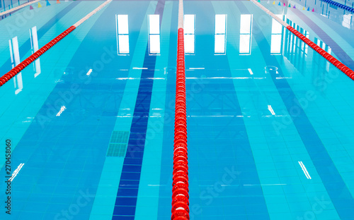 Swimming pool with marked red and white lanes. Empty swimming pool without people with quiet standing water. Water sports in indoor pool.