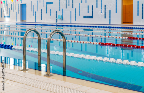 Swimming pool with marked red and white lanes. Empty swimming pool without people with quiet standing water. Water sports in indoor pool.