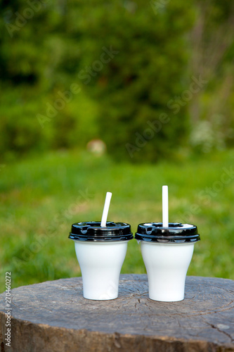 two cocktails in white plastic cups outdoors in the forest