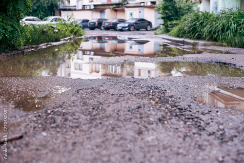 Cuadro en lienzo Broken bad road all in deep puddles after rain in the modern city