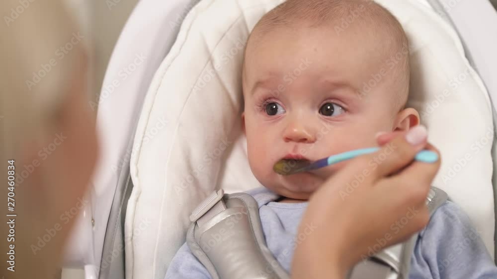 A close-up portrait of a cute infant boy with deep brown eyes fed with a spoon. Nursing a child A close-up portrait of a cute infant boy with deep brown eyes fed with a spoon. Nursing a child