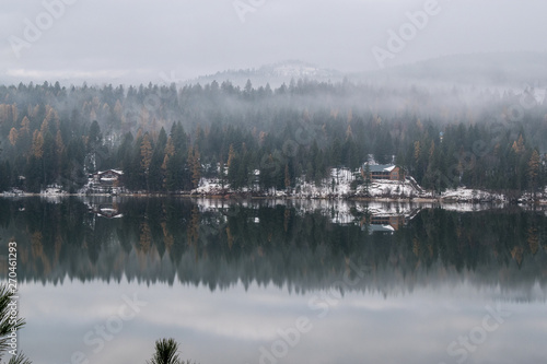 snowy cabin reflected in lake