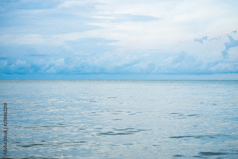 Landscape horizontal skyline of ocean and calm sea with clouded sky in background