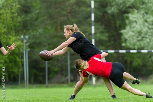 Girls playing american football together outside in summer