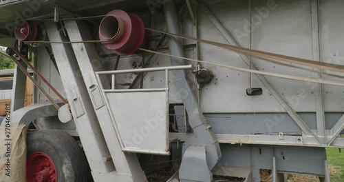 A historic farming machine with fast rotating wheels and belt drives.