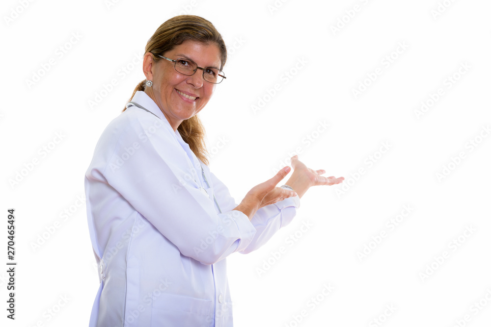 Studio shot of mature happy woman doctor smiling and showing som Studio shot of mature happy woman doctor smiling and showing som
