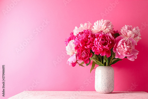 Fototapeta Naklejka Na Ścianę i Meble -  Vase with bouquet of beautiful peonies on pink table against color background, space for text