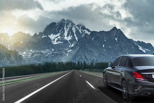 Car drives fast on the highway against the backdrop of a mountain range.