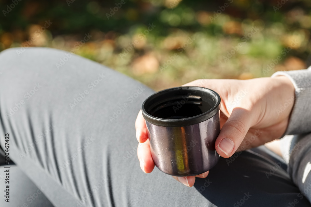 Female hand hold a travel cup with hot beverage in bright sunny day Female hand hold a travel cup with hot beverage in bright sunny day
