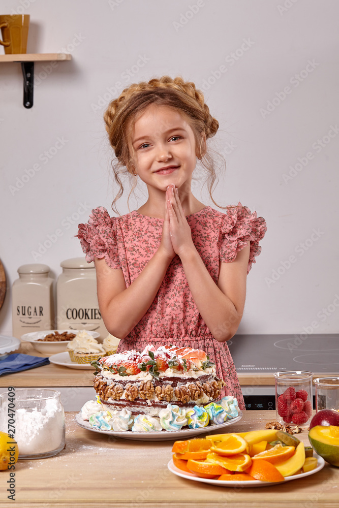 Little girl is making a homemade cake with an easy recipe at kitchen against a white wall with shelves on it. Little girl is making a homemade cake with an easy recipe at kitchen against a white wall with shelves on it.