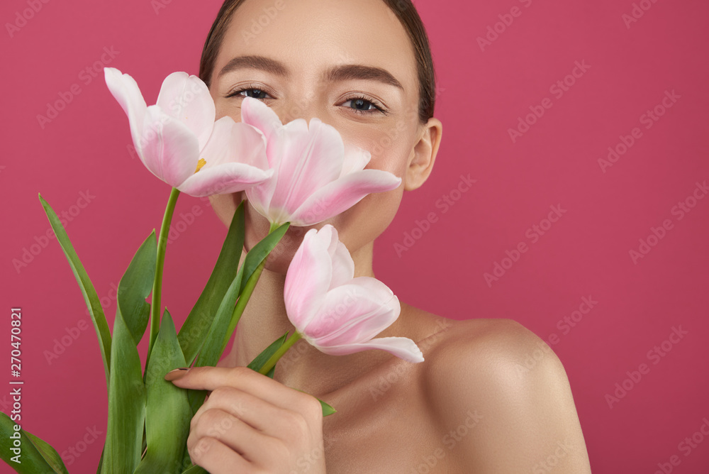 Charming young woman covering face with beautiful tulips