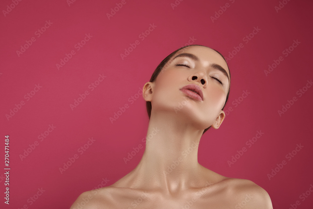 Beautiful serene girl with natural makeup standing against pink background Beautiful serene girl with natural makeup standing against pink background