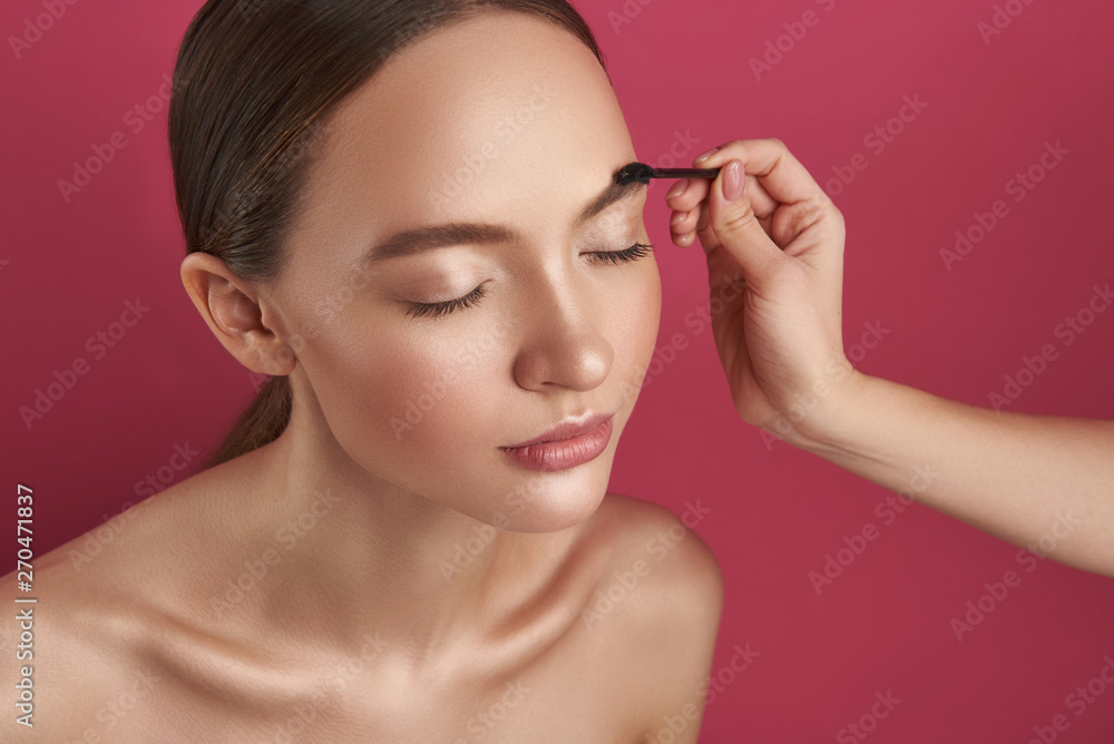 Beautician hand correcting lady eyebrows with brush