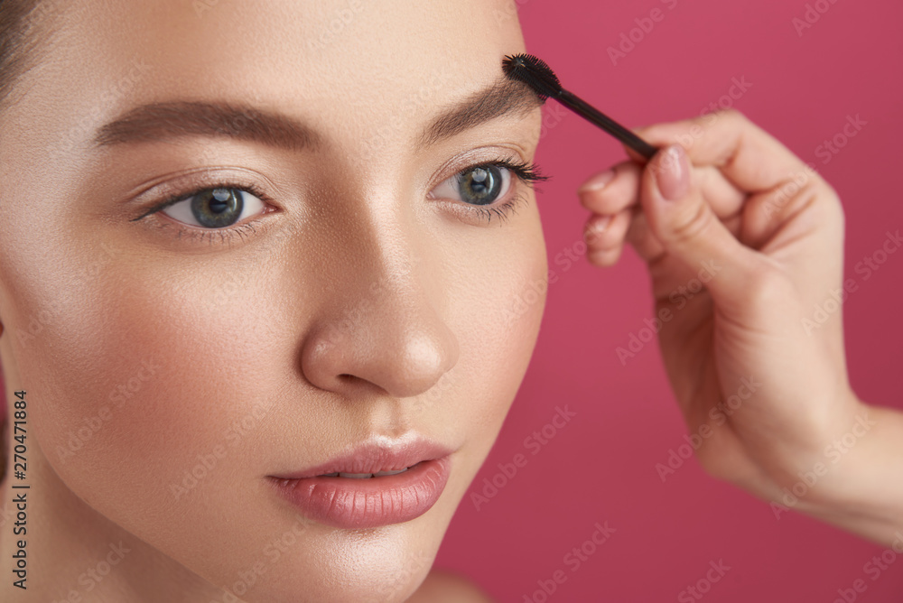 Beautician hand shaping lady brows with brush