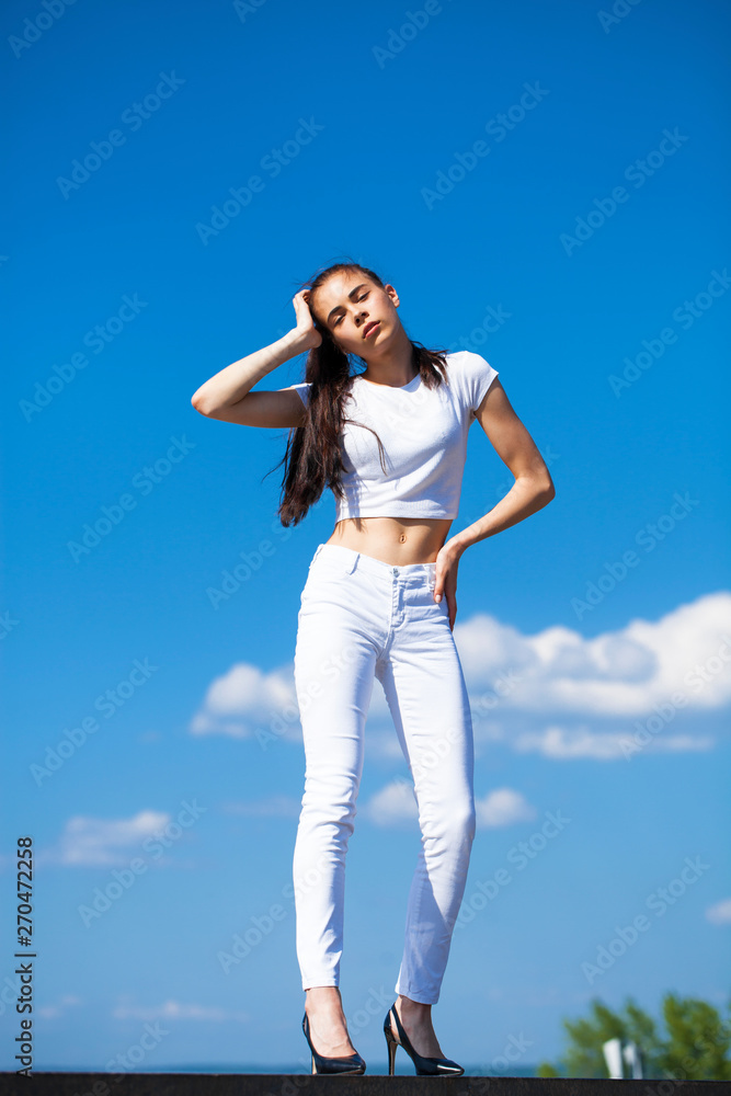 Beautiful brunette woman posing against blue sky bright sunny weather Beautiful brunette woman posing against blue sky bright sunny weather