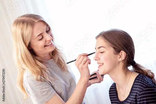 Make-up artist painting beautiful girl eyeshadows.