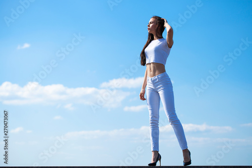 Beautiful brunette woman posing against blue sky bright sunny weather