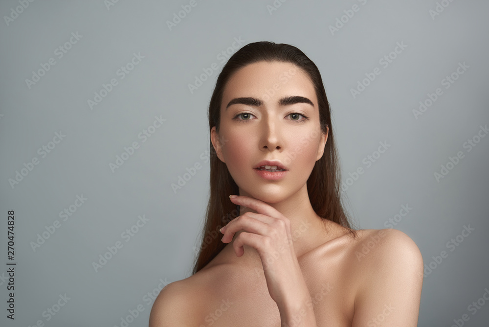Smiling woman with natural make-up is against grey background Smiling woman with natural make-up is against grey background