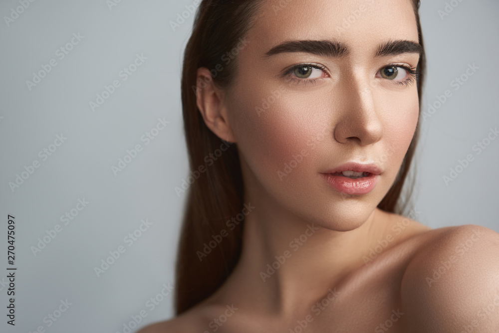 Naklejka premium Tranquil young woman is against grey background