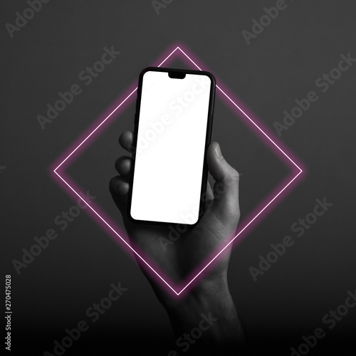 Hand holding modern smartphone with a blank white screen and neon light glow photo