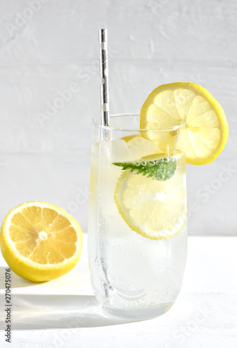 Refreshing drink with ice and lemon on a light background, selective focus