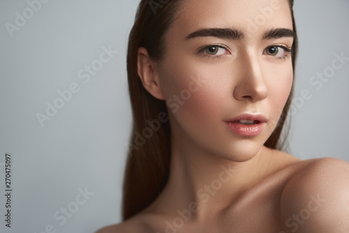 Tranquil young woman is against grey background