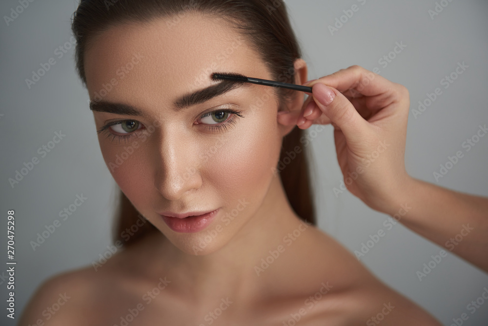 Tranquil woman with nude make-up is having brows styled