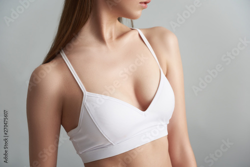 Young woman in white bra isolated on grey background