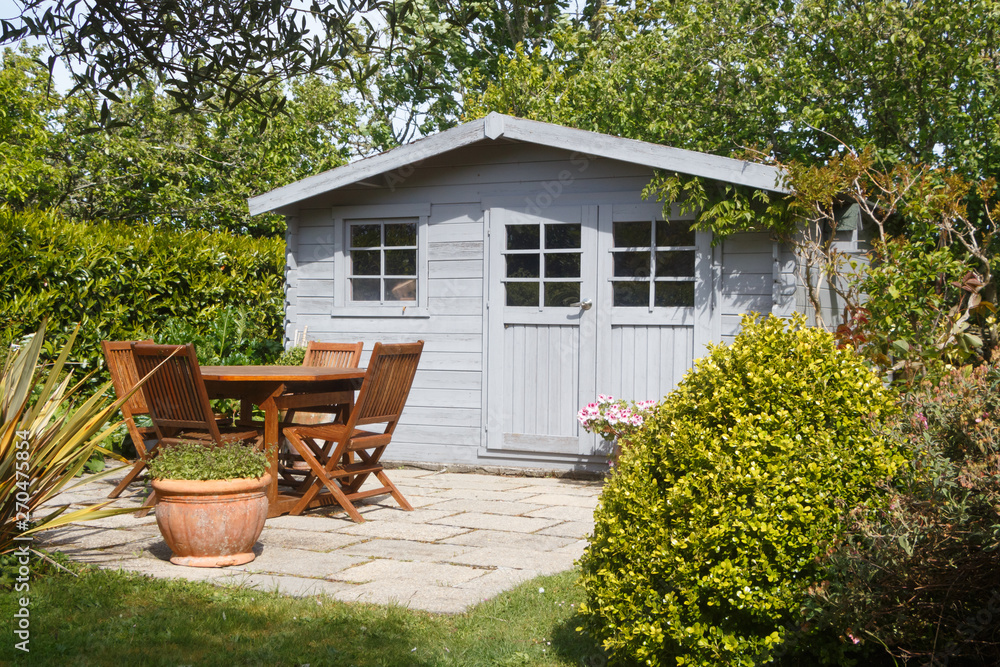 Shed with terrace and wooden garden furniture in a garden during spring - obrazy, fototapety, plakaty 