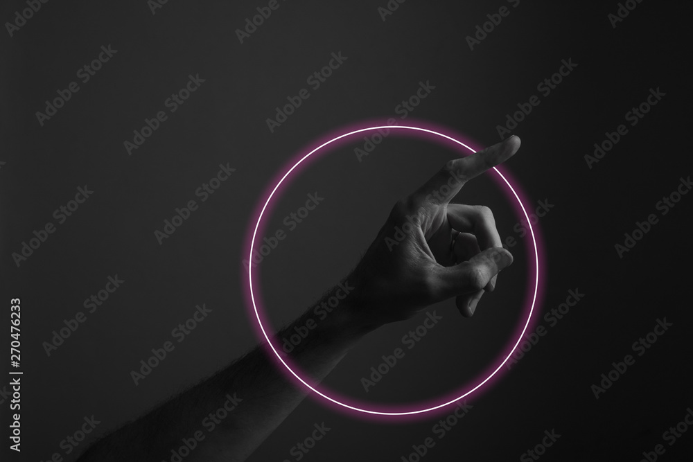 Hand pointing a finger against a dark background with abstract neon ...