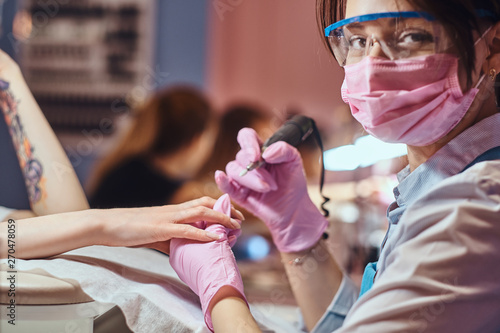 Process of manicure at beuaty salon with two attractive happy womens.  photo