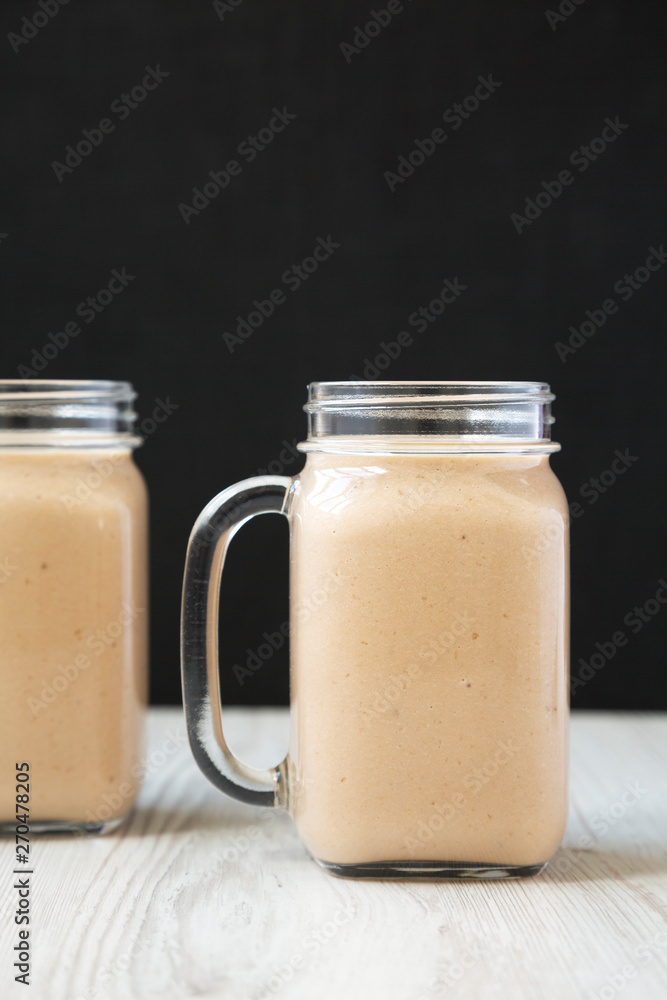 Healthy banana apple smoothie in glass jars, side view. Close-up. Healthy banana apple smoothie in glass jars, side view. Close-up.