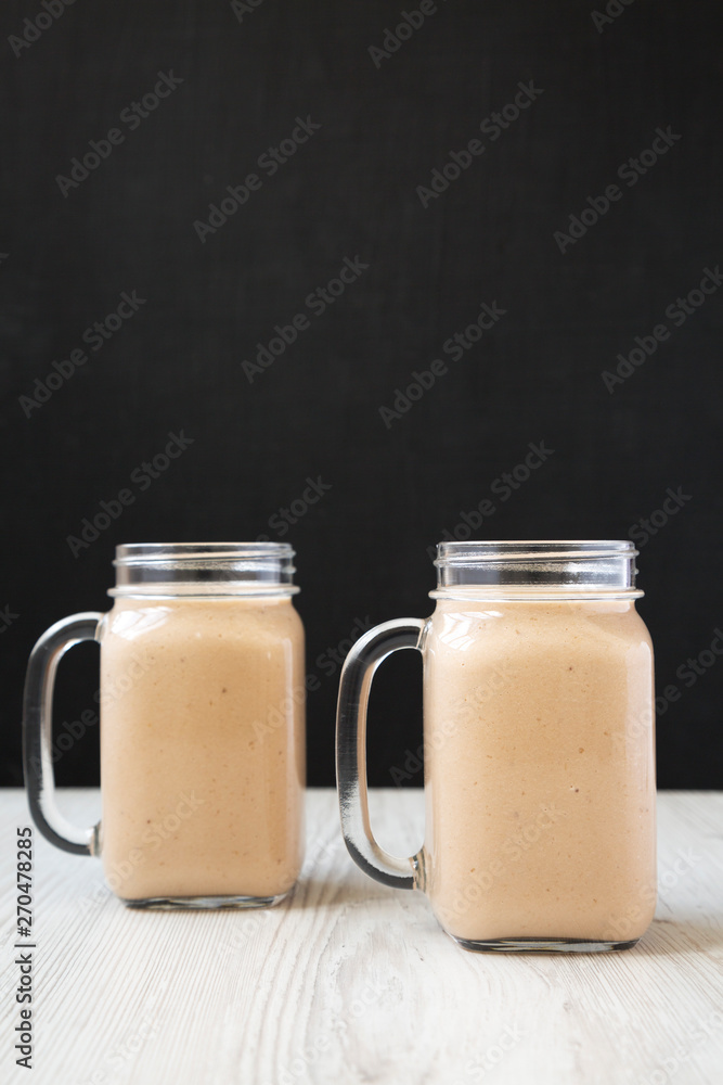 Healthy banana apple smoothie in glass jars, side view. Close-up. Healthy banana apple smoothie in glass jars, side view. Close-up.
