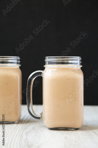 Healthy banana apple smoothie in glass jars  side view. Close-up.