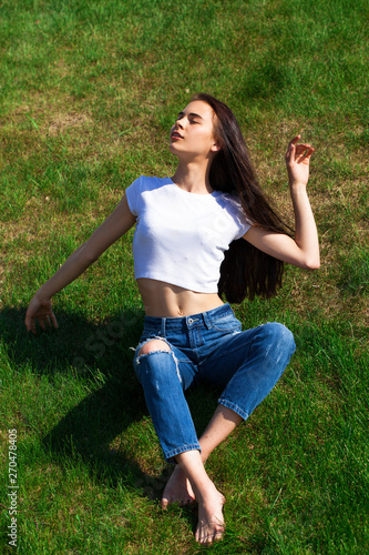 Portrait of a young beautiful girl resting on the lawn in the park