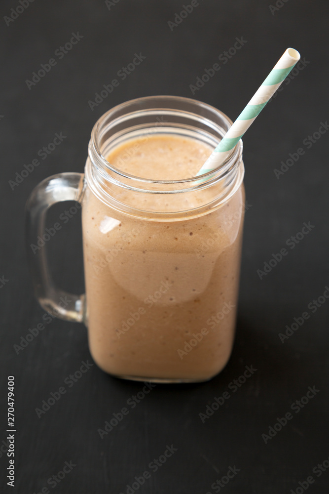 Healthy banana apple smoothie in a glass jar over black background, low angle view. Close-up. Healthy banana apple smoothie in a glass jar over black background, low angle view. Close-up.